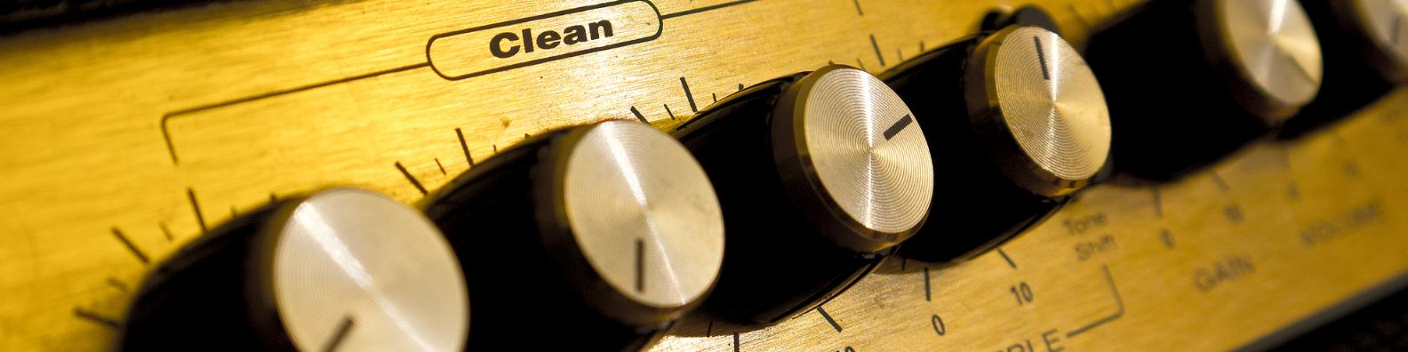 Close-up of a guitar amplifier's control knobs for clean tone, treble, bass, and gain settings.